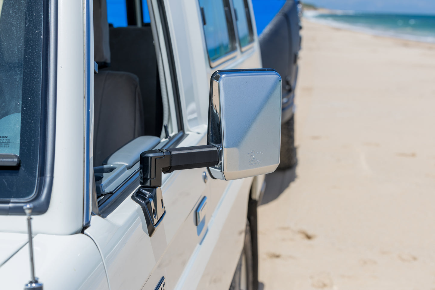 Side view of a Toyota Landcruiser 70 Series vehicle with a mirror extension on a beach