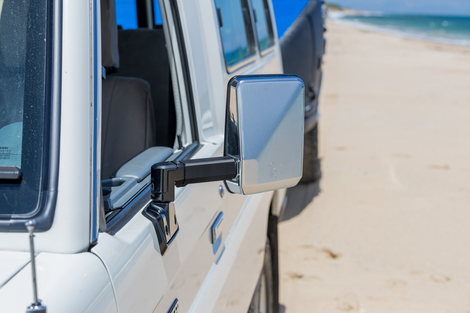 Side view of a Toyota Landcruiser 70 Series vehicle with a mirror extension on a beach